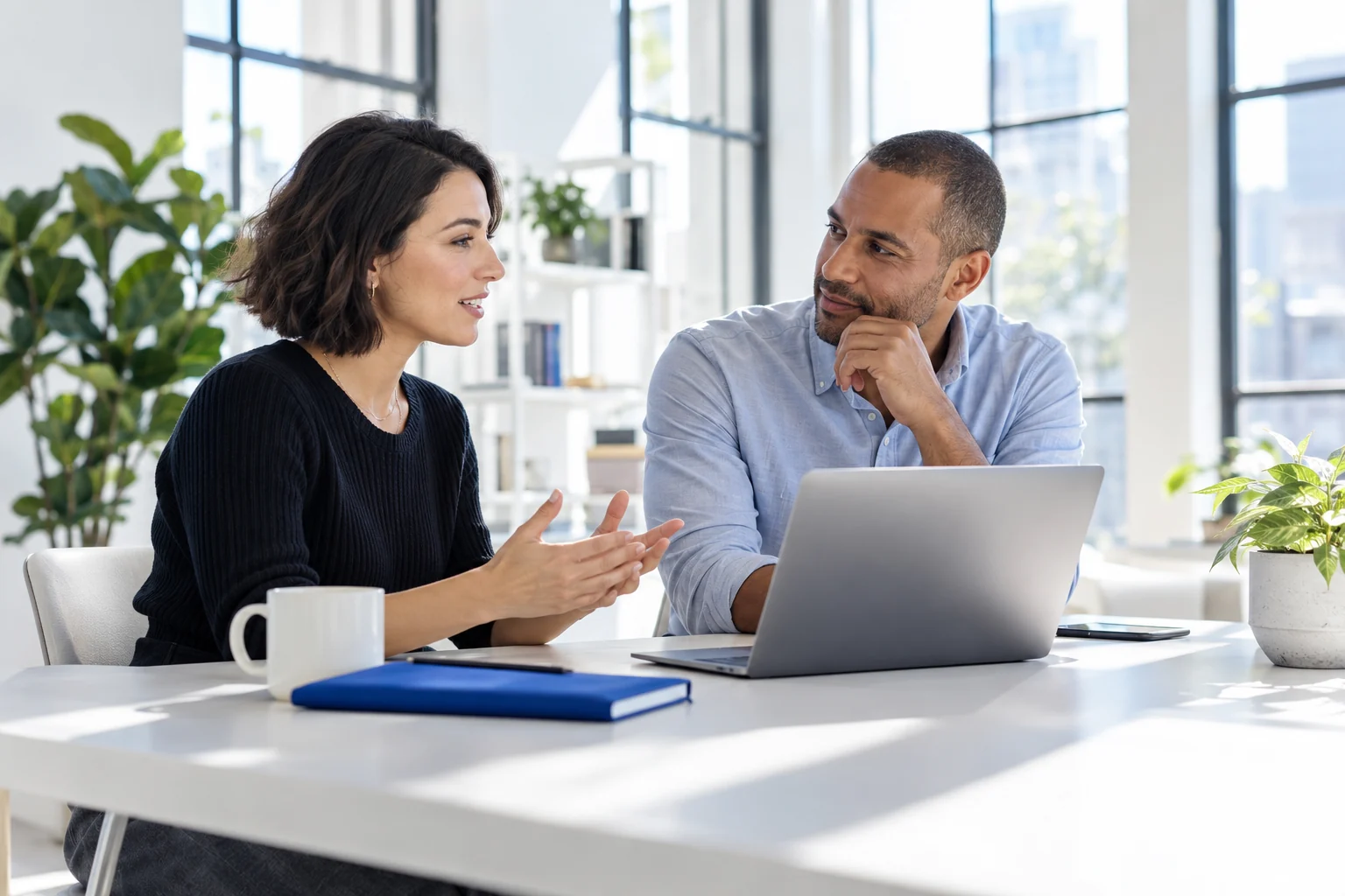 Two business professionals discussing ideas together at a bright workspace